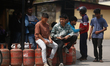 Nepali consumers queue to receive partially filled Liquefied Petroleum Gas (LPG) cylinders...