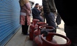People wait in a queue to refill gas cylinders at a gas agency in Sopore, Jammu and Kashmi...