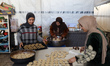 Palestinians displaced from northern Gaza make traditional cookies for the upcoming Eid al...