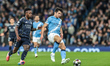 Vinicius Junior of Real Madrid and Abdukodir Khusanov of Manchester City compete for the b...