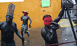 Residents wearing masks and with painted bodies, known as 'Xinacates,' walk the streets of...