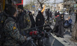 Iranian policemen stand together on a sidewalk as veiled women arrive to participate in a...