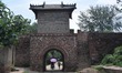 Villagers pass through a gate tower of Linfeng village, a complex built with red rocks, in...