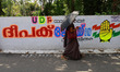 A woman walks past roadside election graffiti of Deepak Joy, United Democratic Front (UDF)...