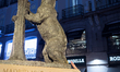 A woman reaches toward the El Oso y el Madrono statue at Puerta del Sol in Madrid, Spain,...