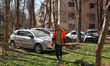 A municipal worker walks past cars parked outside an apartment block damaged by a drone st...