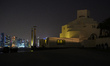 People walk past the Museum of Islamic Art as the lights are turned off for Earth Hour in...