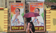 A woman walks past cutouts promoting TMC candidate Mamata Banerjee for the upcoming West B...
