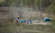 Tents, clothing, and scattered belongings are seen in an informal riverside encampment amo...