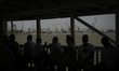 Passengers sit under shade aboard a ferry boat on the Arabian Sea as industrial cranes and...