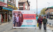 Men walk next to an awareness board for the Census 2027 in Srinagar, Jammu and Kashmir, on...