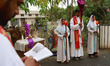 A Christian priest and altar girls pray by the roadside during a Good Friday procession in...