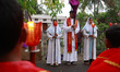 A Christian priest and altar girls pray by the roadside during a Good Friday procession in...