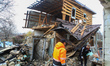 Men clear debris outside a house damaged by a drone strike in Hatne, Kyiv region, Ukraine,...