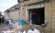 A man throws debris out of a window of a house damaged by a drone strike in Hatne, Kyiv re...