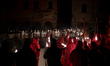 A hooded penitent from a local religious confraternity known as confratelli waits for the...