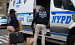 Members of the NYPD Crime Scene Unit collect evidence inside an apartment complex near Dav...