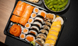 A takeaway sushi set with salmon hosomaki, futomaki, and omelette-wrapped rolls is arrange...