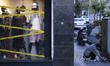 A young Iranian man feeds a stray cat as tape covers the windows of his dress shop to prot...