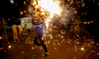 A person runs with the traditional 'Torito' (cardboard bull) while setting off fireworks i...