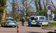 Police officers stand beside police vehicles during a search for a person near Bad Wimpfen...