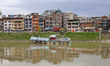 Locals watch as people retrieve belongings from a partially submerged houseboat on the wat...
