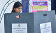 A woman casts her ballot at a polling station during the Assam Legislative Assembly electi...