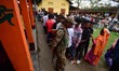 Voters stand in queues to cast their ballots at a polling booth during the Assam Legislati...