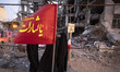 Pro-government supporters gather in front of the ruins of a building in a residential area...