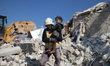 Civil defense workers rescue a child from beneath the rubble following the earthquake that...