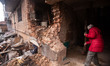 A resident sweeps the shattered entrance to her apartment block in the city of Sumy, Ukrai...