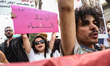 A female protester holds a placard in Arabic reading, ''No guardianship over women's bodie...