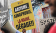 A demonstrator holds a placard reading, ''racism, xenophobia, hate out!'' while others sho...