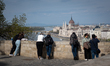People stand on a terrace in the Castle District (Budai Var) overlooking the Danube River...