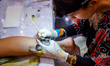 A tattoo artist works on a customer's leg during the 13th International Nepal Tattoo Conve...