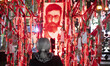 An Iranian woman stands in front of a religious symbol with a portrait of Iran's late Supr...
