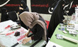 Veiled pro-government supporters prepare headbands while participating in a state-run work...