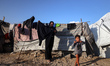 A displaced Palestinian woman hangs laundry inside Gaza City's port on April 13, 2026. Bot...