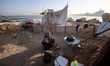 A displaced Palestinian woman washes dishes in front of her tent inside Gaza City's port o...