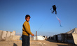 A displaced Palestinian child flies a kite outside a family tent in Gaza City, Gaza, on Ap...