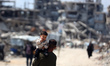 People walk past the rubble of destroyed buildings in the Jabalia camp for Palestinian ref...
