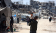 People walk past the rubble of destroyed buildings in the Jabalia camp for Palestinian ref...