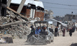 People walk past the rubble of destroyed buildings in the Jabalia camp for Palestinian ref...