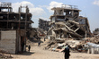 People walk past the rubble of destroyed buildings in the Jabalia camp for Palestinian ref...