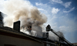 Rescuers use a telescopic ladder and an aerial work platform to extinguish a fire in an of...