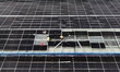 Construction workers install photovoltaic modules on the roof of the factory building of J...