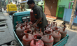 A delivery man records a delivery and collects payment while delivering an LPG cylinder to...