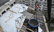 A boom lifts a funnel skip filled with cement to the top floors of a nine-storey apartment...
