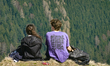 Two young hikers rest on a grassy slope overlooking Lake Tegernsee in Tegernsee, Bavaria,...