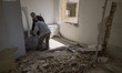Two Iranian volunteers work at a building damaged in a military operation in the Shahid Bo...